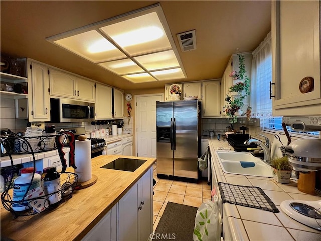 kitchen with sink, appliances with stainless steel finishes, tasteful backsplash, and light tile patterned flooring