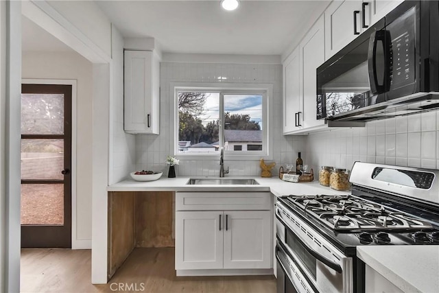 kitchen featuring double oven range, light hardwood / wood-style floors, decorative backsplash, white cabinets, and sink