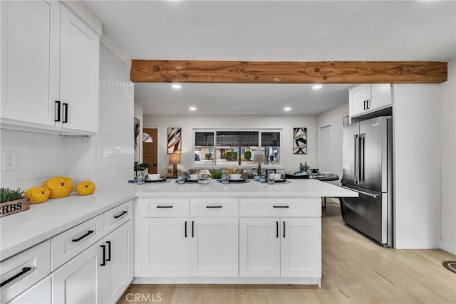 kitchen with white cabinetry, beam ceiling, kitchen peninsula, and high end refrigerator