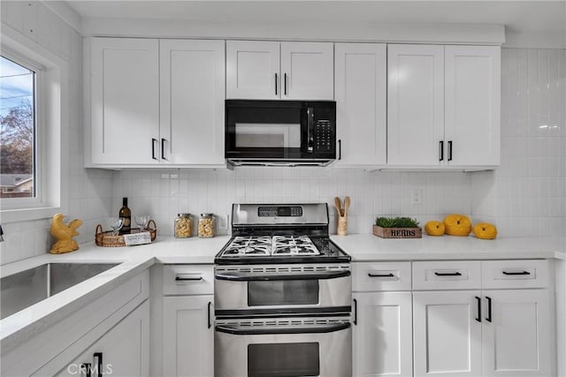 kitchen with double oven range, decorative backsplash, white cabinets, and sink