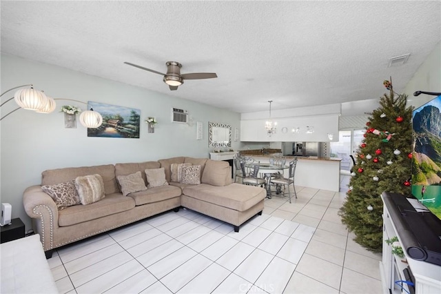 living room with ceiling fan with notable chandelier, a textured ceiling, a wall mounted AC, and light tile patterned flooring