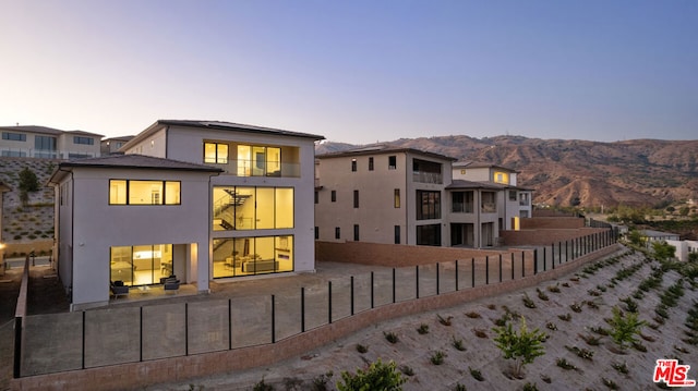 back house at dusk with a mountain view and a patio