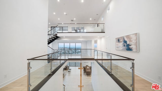 stairs with hardwood / wood-style floors and a towering ceiling