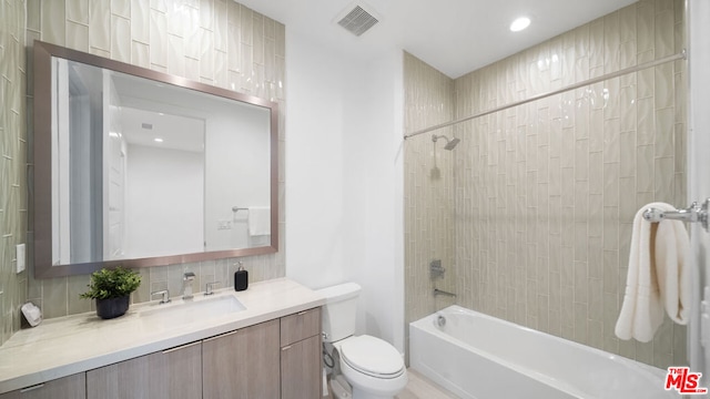 full bathroom with toilet, decorative backsplash, tiled shower / bath, and vanity