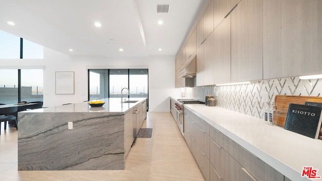 kitchen with decorative backsplash, a spacious island, a wealth of natural light, and light stone countertops