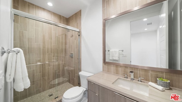 bathroom featuring toilet, decorative backsplash, an enclosed shower, and vanity