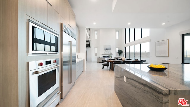 kitchen featuring a towering ceiling and built in appliances