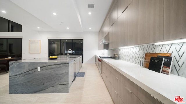 kitchen featuring light stone countertops, sink, decorative backsplash, and gas cooktop