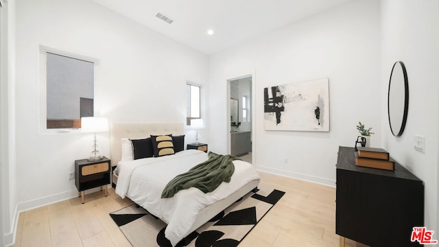 bedroom with ensuite bathroom and light wood-type flooring