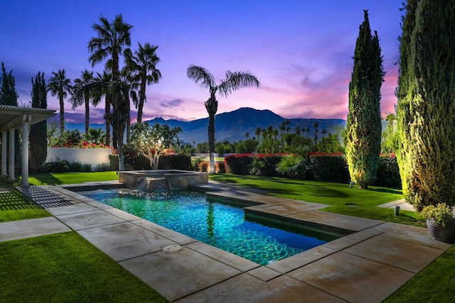 pool at dusk featuring a pergola, a mountain view, an in ground hot tub, and a lawn