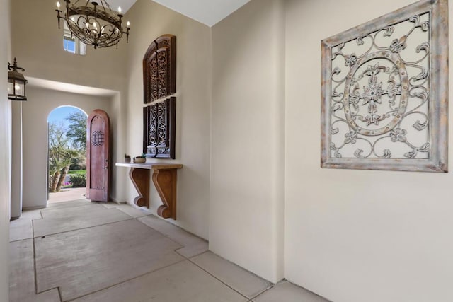 hallway with an inviting chandelier and a towering ceiling