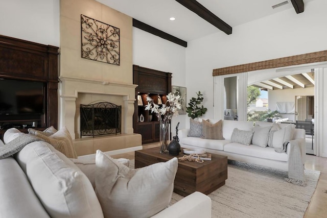 living room featuring a tiled fireplace and beamed ceiling