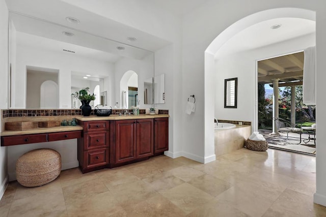 bathroom with vanity and tiled tub