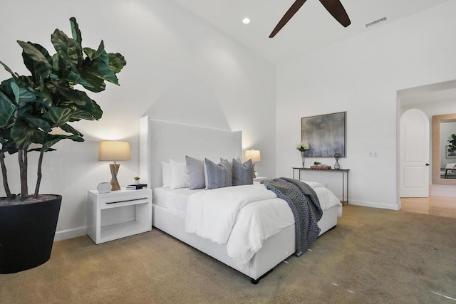 carpeted bedroom with ceiling fan and high vaulted ceiling