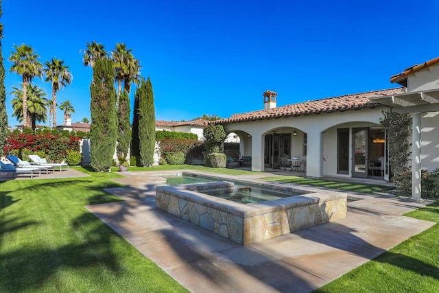 back of house with a swimming pool with hot tub, a lawn, and a patio