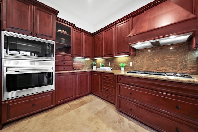 kitchen featuring decorative backsplash, light stone counters, premium range hood, and stainless steel appliances