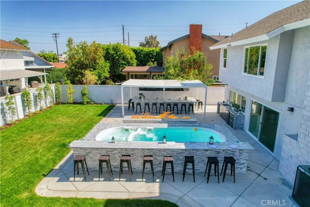 view of swimming pool featuring a patio area, a bar, and a lawn