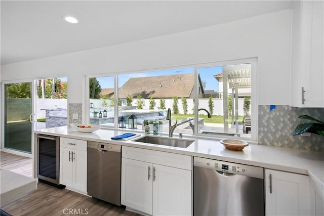 kitchen featuring stainless steel dishwasher, wine cooler, decorative backsplash, and sink