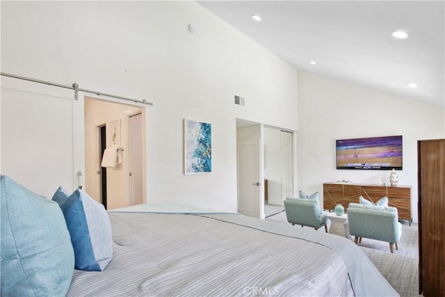 bedroom with a closet, a barn door, and high vaulted ceiling