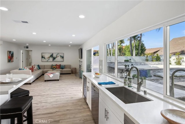 kitchen featuring light wood-type flooring, stainless steel dishwasher, white cabinets, and sink