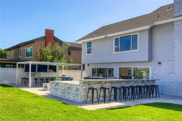 back of house featuring a lawn and a bar