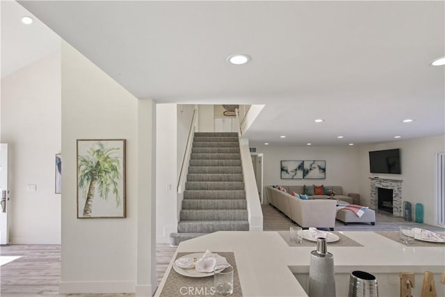 stairs featuring a stone fireplace and hardwood / wood-style flooring