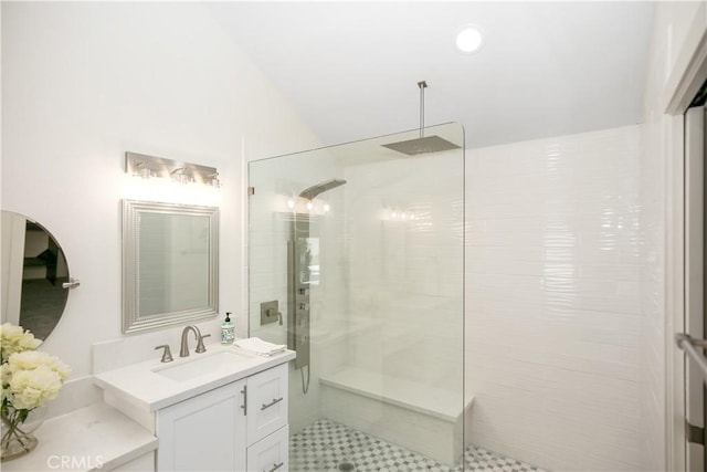 bathroom with lofted ceiling, a tile shower, and vanity