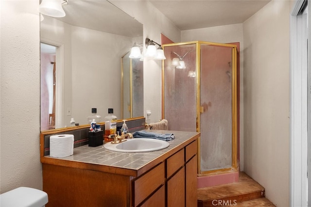 bathroom featuring a shower with shower door, toilet, and vanity