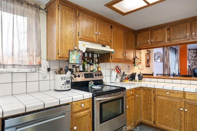 kitchen with stainless steel appliances, tile countertops, and tasteful backsplash