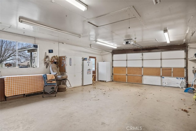 garage featuring white fridge and a garage door opener