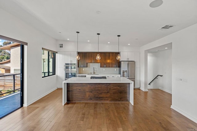 kitchen with decorative light fixtures, a healthy amount of sunlight, stainless steel appliances, and a kitchen island