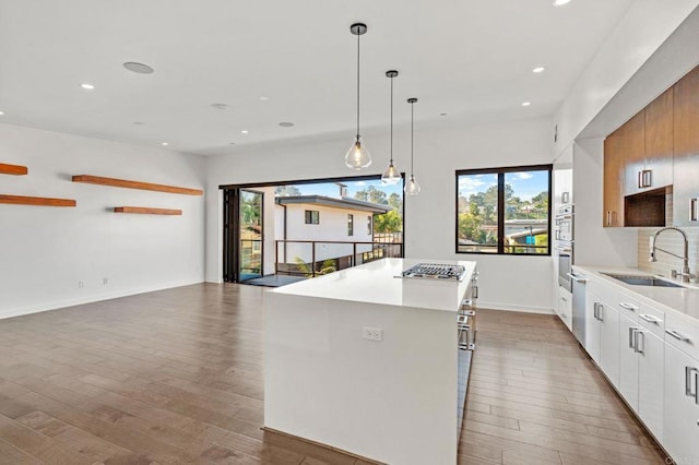 kitchen featuring white cabinetry, decorative light fixtures, sink, dark wood-type flooring, and a center island