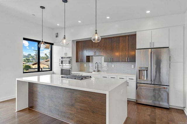 kitchen with a center island, sink, white cabinetry, appliances with stainless steel finishes, and dark brown cabinets