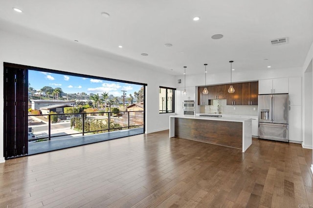 kitchen with hardwood / wood-style floors, stainless steel appliances, tasteful backsplash, pendant lighting, and a center island