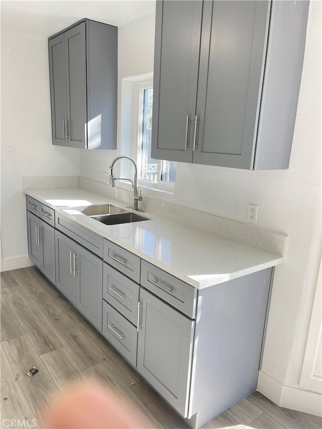 kitchen with sink, gray cabinets, and light hardwood / wood-style flooring