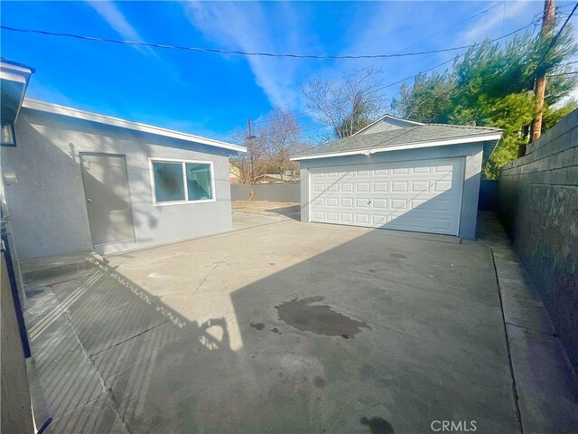 view of patio / terrace with a garage and an outbuilding