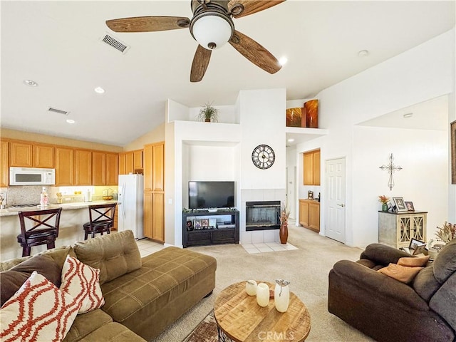 living room featuring light carpet, ceiling fan, a fireplace, and lofted ceiling