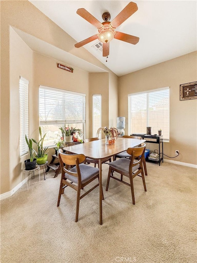 carpeted dining area with ceiling fan and lofted ceiling