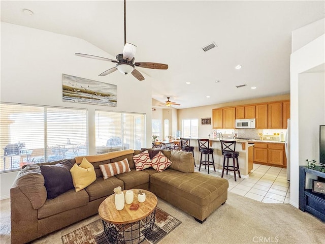 living room with ceiling fan, light tile patterned floors, lofted ceiling, and a healthy amount of sunlight