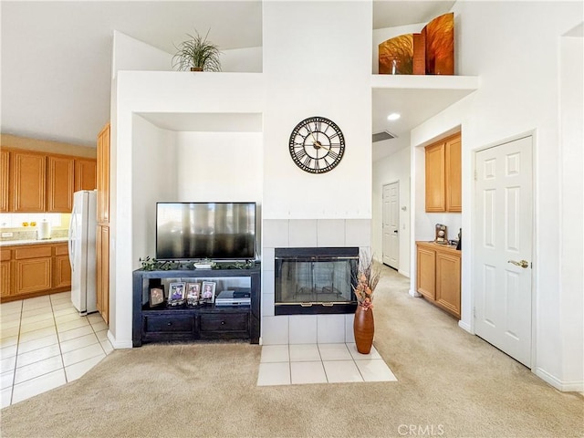 living room featuring light carpet, a fireplace, and a high ceiling