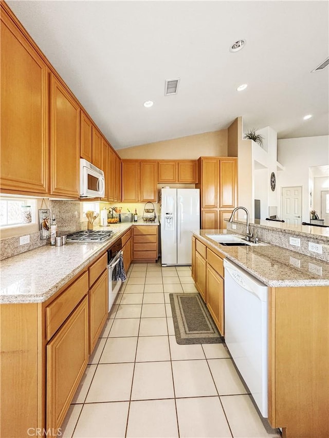 kitchen featuring lofted ceiling, stainless steel appliances, sink, light stone counters, and light tile patterned floors