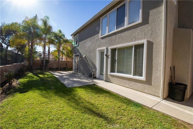 back of house with a lawn and a patio