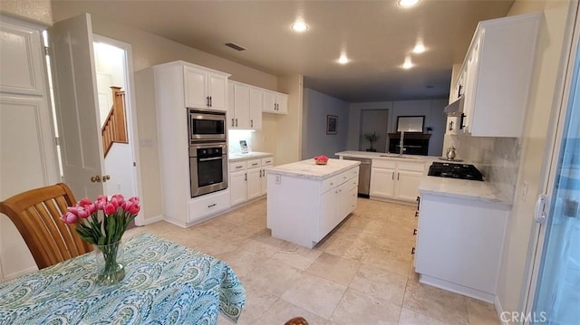 kitchen with white cabinets, backsplash, a center island, kitchen peninsula, and stainless steel appliances