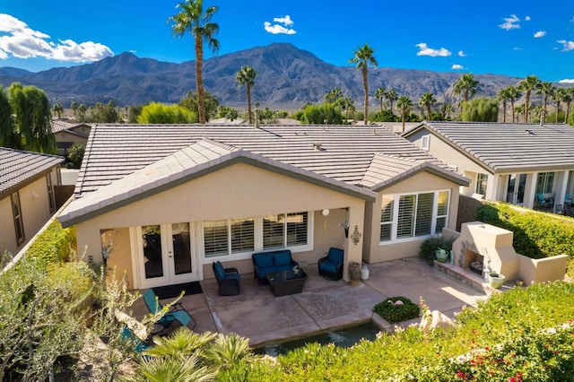 rear view of house with an outdoor living space, a mountain view, and a patio