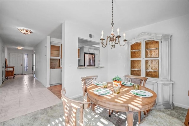 dining space with baseboards, light tile patterned floors, visible vents, and a notable chandelier