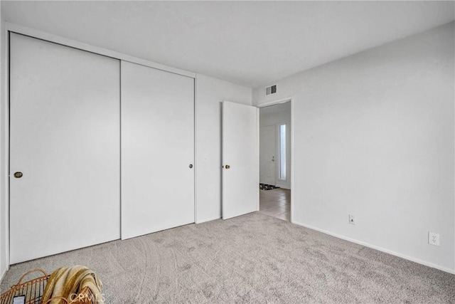 unfurnished bedroom with light carpet, a closet, and visible vents