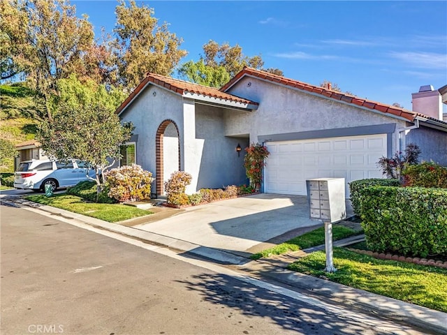 mediterranean / spanish house with concrete driveway, a tile roof, a chimney, an attached garage, and stucco siding