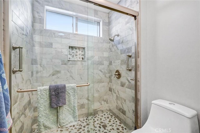 bathroom featuring toilet and a stall shower