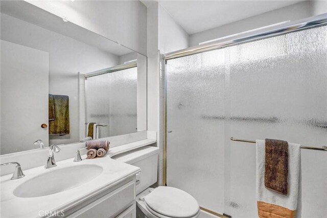 bathroom featuring toilet, a stall shower, and vanity