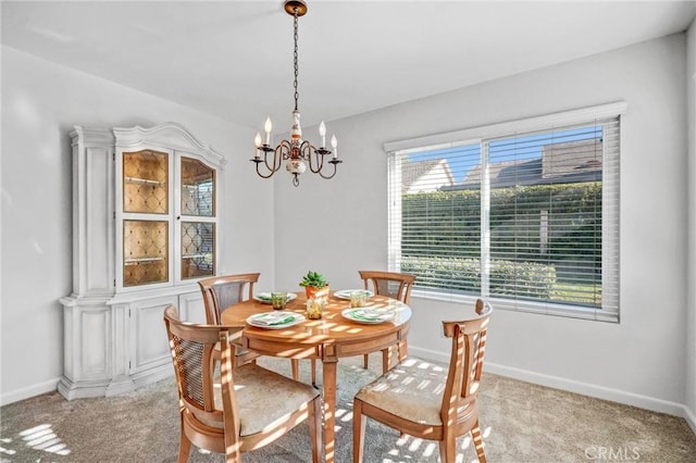 dining room featuring light colored carpet, baseboards, and an inviting chandelier